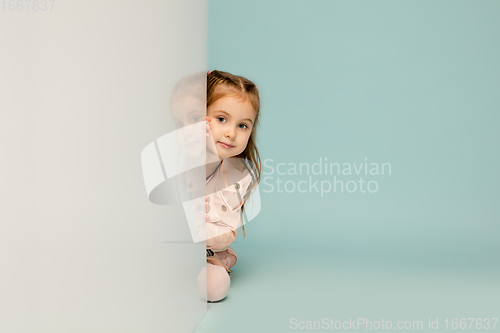 Image of Happy kid, girl isolated on blue studio background. Looks happy, cheerful, sincere. Copyspace. Childhood, education, emotions concept