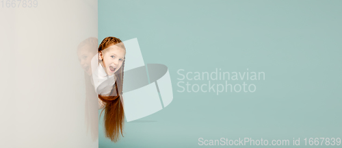 Image of Happy kid, girl isolated on blue studio background. Looks happy, cheerful, sincere. Copyspace. Childhood, education, emotions concept