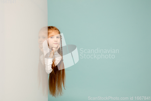 Image of Happy kid, girl isolated on blue studio background. Looks happy, cheerful, sincere. Copyspace. Childhood, education, emotions concept