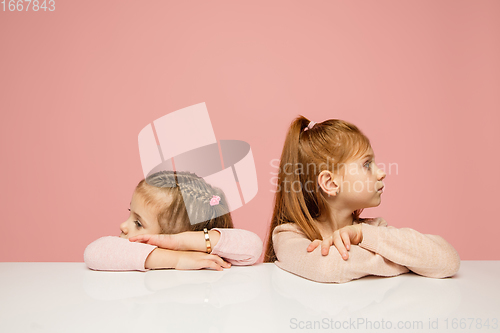 Image of Happy kids, girls isolated on coral pink studio background. Look happy, cheerful, sincere. Copyspace. Childhood, education, emotions concept