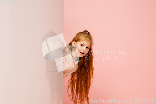 Image of Happy kid, girl isolated on coral pink studio background. Looks happy, cheerful, sincere. Copyspace. Childhood, education, emotions concept