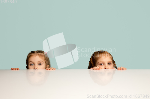 Image of Happy kids, girls isolated on blue studio background. Look happy, cheerful, sincere. Copyspace. Childhood, education, emotions concept