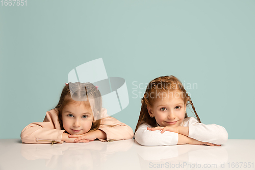 Image of Happy kids, girls isolated on blue studio background. Look happy, cheerful, sincere. Copyspace. Childhood, education, emotions concept