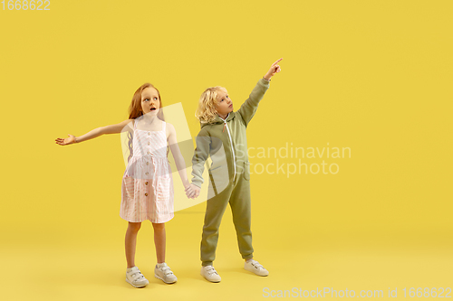 Image of Childhood and dream about big and famous future. Boy and girl isolated on yellow studio background