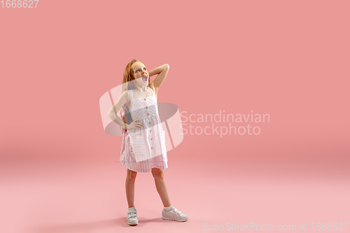 Image of Childhood and dream about big and famous future. Pretty longhair girl isolated on coral pink background