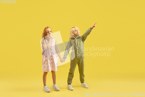 Image of Childhood and dream about big and famous future. Boy and girl isolated on yellow studio background