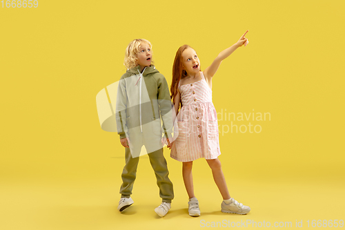 Image of Childhood and dream about big and famous future. Boy and girl isolated on yellow studio background