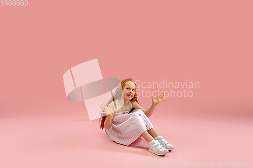 Image of Childhood and dream about big and famous future. Pretty longhair girl isolated on coral pink background