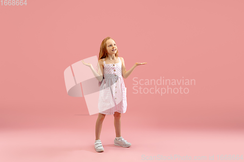 Image of Childhood and dream about big and famous future. Pretty longhair girl isolated on coral pink background