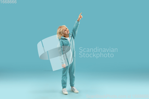 Image of Childhood and dream about big and famous future. Pretty curly boy isolated on blue background