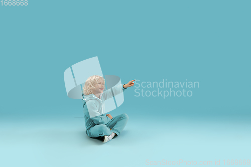 Image of Childhood and dream about big and famous future. Pretty curly boy isolated on blue background