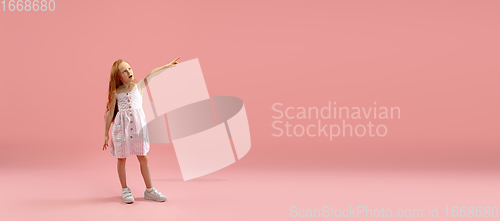 Image of Childhood and dream about big and famous future. Pretty longhair girl isolated on coral pink background