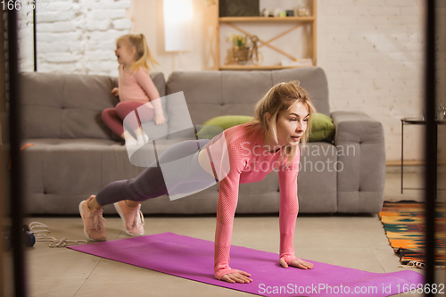 Image of Young woman exercising fitness, aerobic, yoga at home, sporty lifestyle. Getting active while her child playing on the background, home gym.