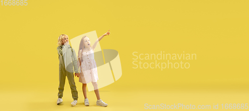 Image of Childhood and dream about big and famous future. Boy and girl isolated on yellow studio background