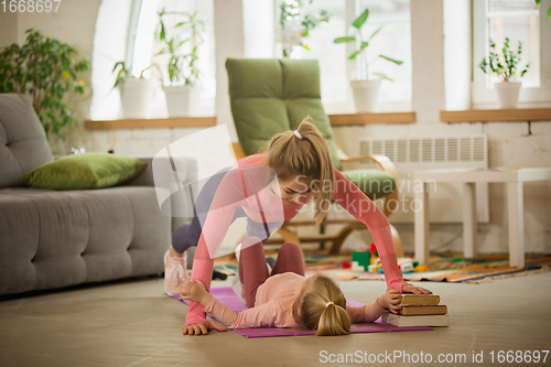 Image of Young woman exercising fitness, aerobic, yoga at home, sporty lifestyle. Getting active with her child playing, home gym.