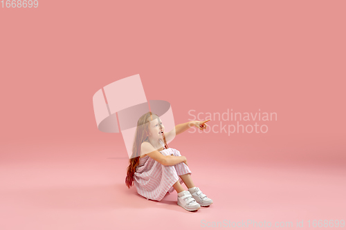 Image of Childhood and dream about big and famous future. Pretty longhair girl isolated on coral pink background