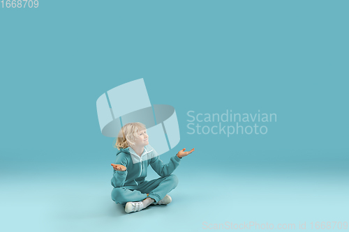 Image of Childhood and dream about big and famous future. Pretty curly boy isolated on blue background