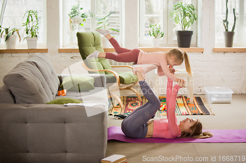 Image of Young woman exercising fitness, aerobic, yoga at home, sporty lifestyle. Getting active with her child playing, home gym.