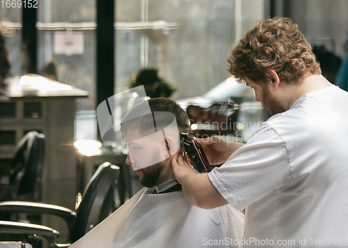 Image of Close up master barber, stylist does the hairstyle to guy, young