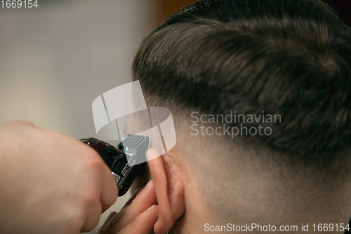 Image of Close up of client of master barber, stylist during getting care of hairstyle. Professional occupation, male beauty concept