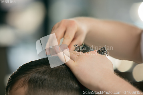 Image of Close up hands of master barber, stylist does the hairstyle to guy, young man. Professional occupation, male beauty concept
