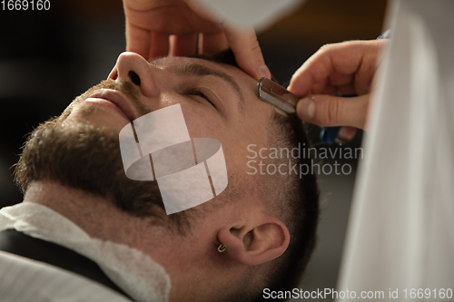 Image of Close up hands of master barber, stylist does the hairstyle to guy, young man. Professional occupation, male beauty concept