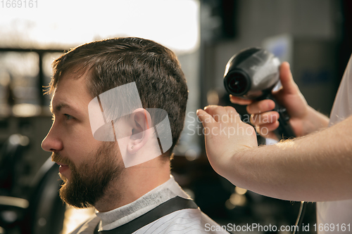 Image of Close up of client of master barber, stylist during getting care of hairstyle. Professional occupation, male beauty concept