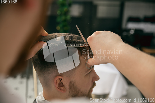 Image of Close up master barber, stylist does the hairstyle to guy, young