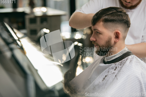 Image of Close up master barber, stylist does the hairstyle to guy, young
