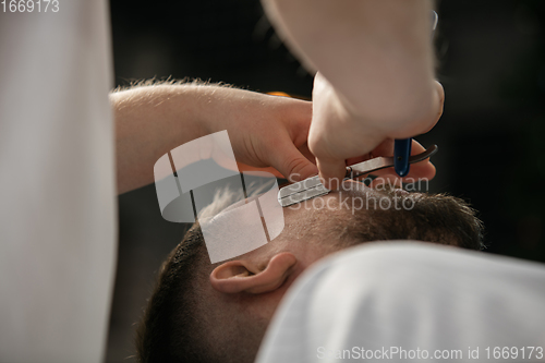 Image of Close up hands of master barber, stylist does the hairstyle to guy, young man. Professional occupation, male beauty concept