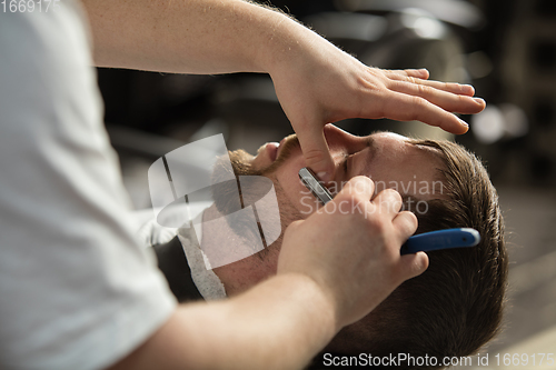 Image of Close up hands of master barber, stylist does the hairstyle to guy, young man. Professional occupation, male beauty concept