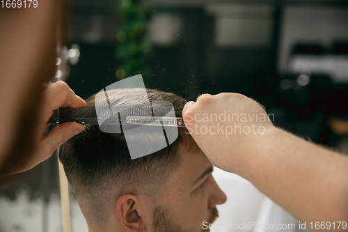 Image of Close up master barber, stylist does the hairstyle to guy, young