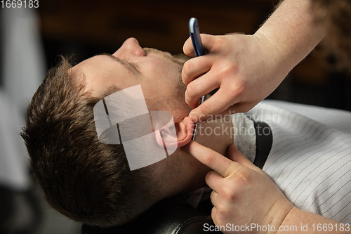 Image of Close up hands of master barber, stylist does the hairstyle to guy, young man. Professional occupation, male beauty concept