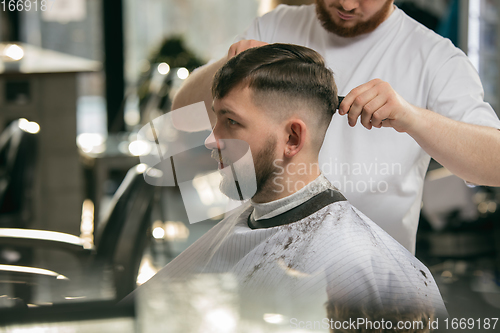 Image of Close up master barber, stylist does the hairstyle to guy, young