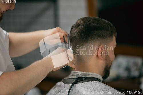 Image of Close up master barber, stylist does the hairstyle to guy, young man. Professional occupation, male beauty concept