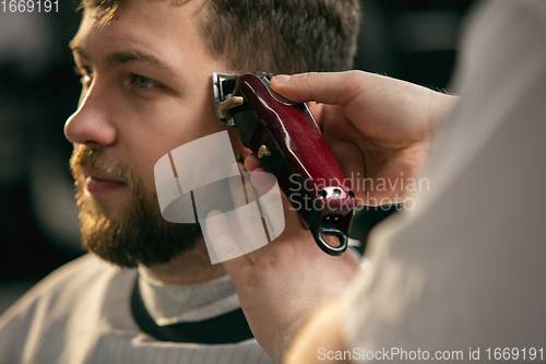 Image of Close up of client of master barber, stylist during getting care of hairstyle. Professional occupation, male beauty concept