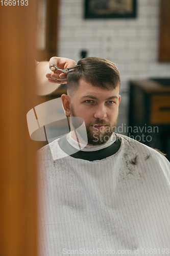 Image of Close up of client of master barber, stylist during getting care of hairstyle. Professional occupation, male beauty concept