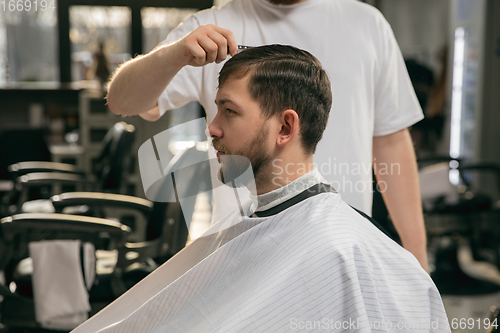 Image of Close up of client of master barber, stylist during getting care of hairstyle. Professional occupation, male beauty concept