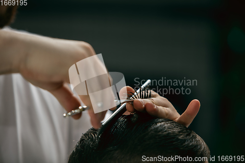 Image of Close up hands of master barber, stylist does the hairstyle to g