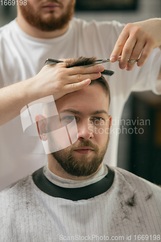 Image of Close up master barber, stylist does the hairstyle to guy, young man. Professional occupation, male beauty concept