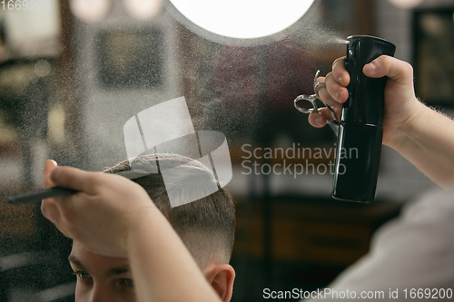 Image of Close up of client of master barber, stylist during getting care of hairstyle. Professional occupation, male beauty concept