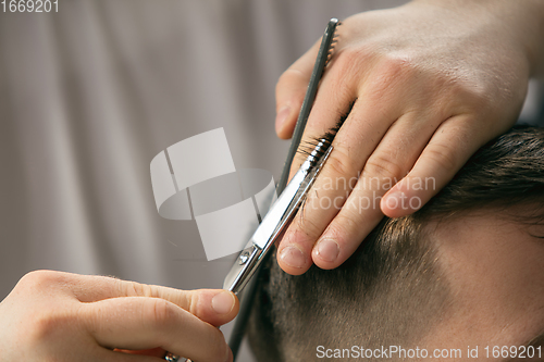 Image of Close up hands of master barber, stylist does the hairstyle to guy, young man. Professional occupation, male beauty concept