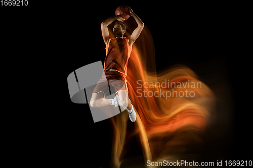 Image of Young arabian basketball player of team in action, motion isolated on black background in mixed light. Concept of sport, movement, energy and dynamic.