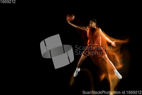 Image of Young arabian basketball player of team in action, motion isolated on black background in mixed light. Concept of sport, movement, energy and dynamic.