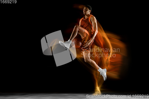 Image of Young arabian basketball player of team in action, motion isolated on black background in mixed light. Concept of sport, movement, energy and dynamic.