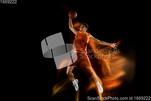 Image of Young arabian basketball player of team in action, motion isolated on black background in mixed light. Concept of sport, movement, energy and dynamic.