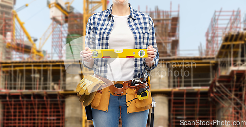 Image of woman builder with level and working tools on belt