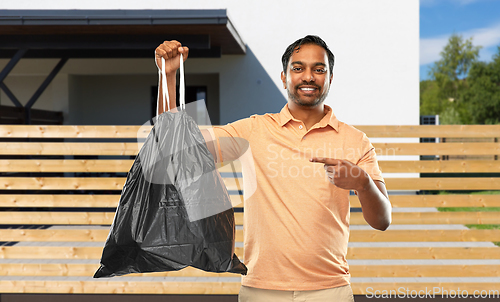 Image of smiling indian man holding trash bag