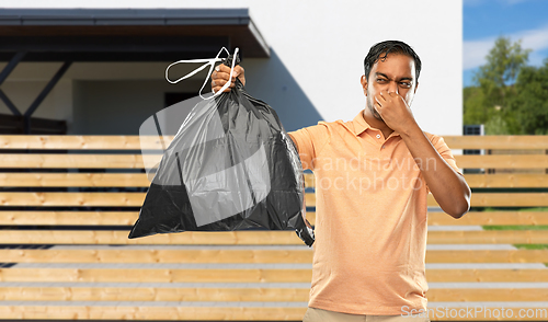 Image of indian man holding stinky trash bag