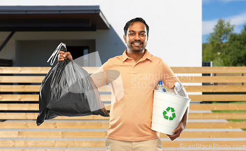 Image of smiling indian man sorting paper and plastic waste